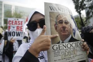 Γυναίκα δείχνει το πρόσωπο Νετανιάχου σε πόστερ σε διαδήλωση