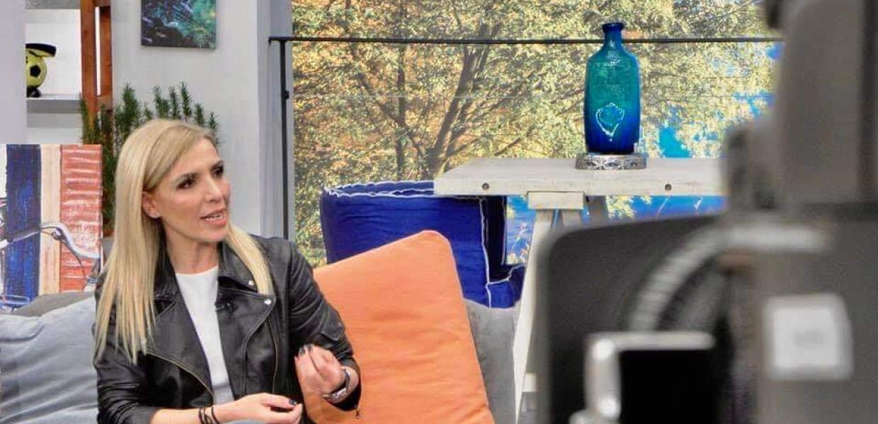 Η δημοσιογράφος Ρένα Κουβελιώτη καθισμένη σε καναπέ σε πλατό εκπομπής