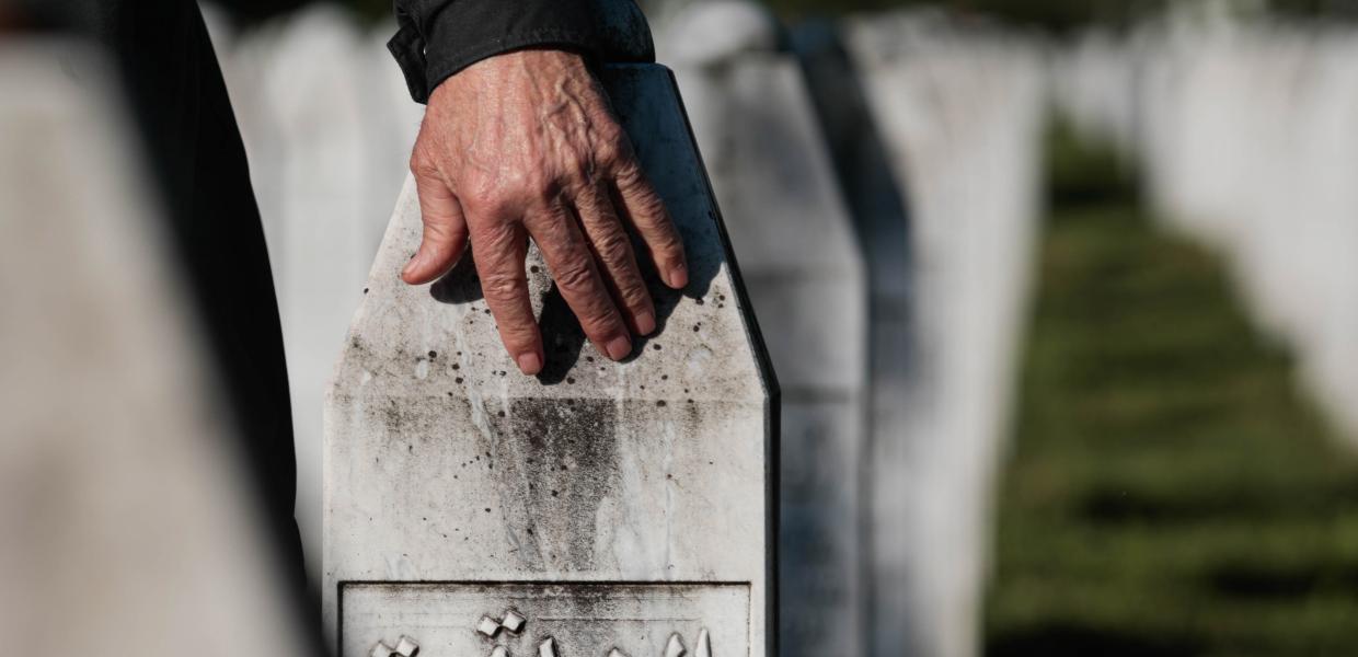  Ένας άνδρας τοποθετεί το χέρι του σε μια ταφόπλακα κατά τη διάρκεια τελετής για την σφαγή στη Σρεμπρένιτσα